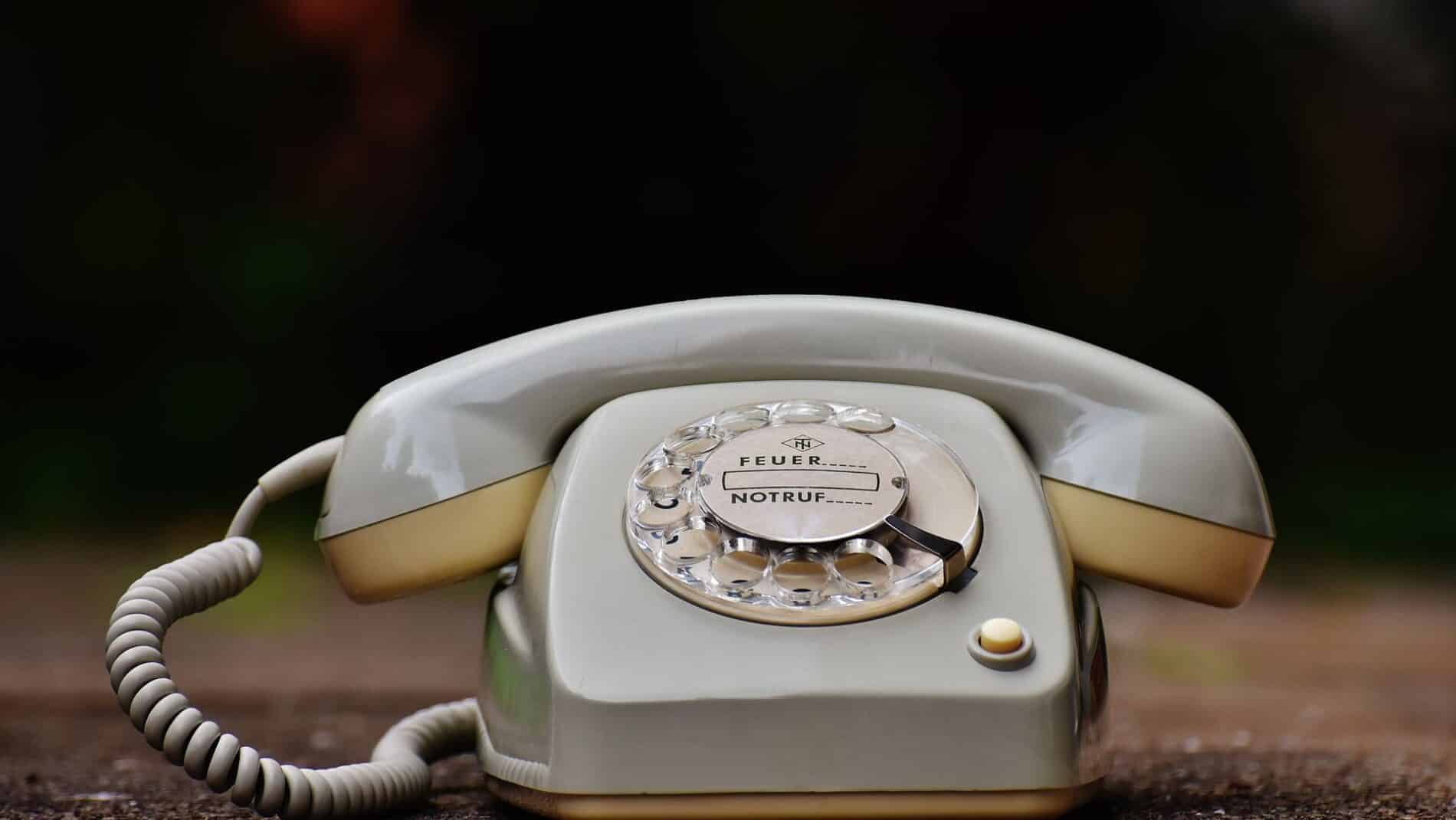 Close-up of a vintage rotary dial telephone with a nostalgic design on a wooden surface.