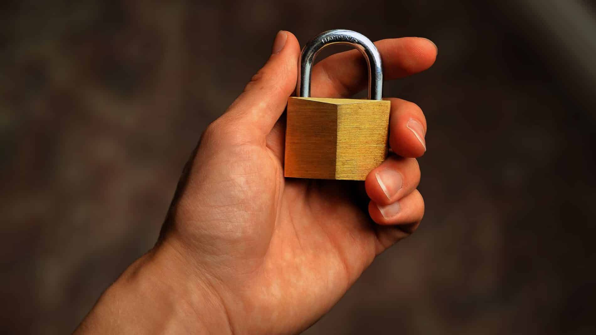 Hand holding a brass padlock, symbolizing security and protection